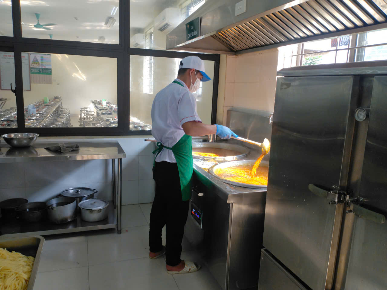 A person in a white hat and apron cooking food in a kitchen

Description automatically generated