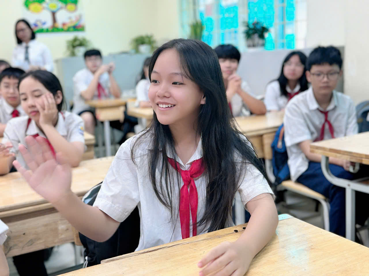A child in a uniform raising her handDescription automatically generated