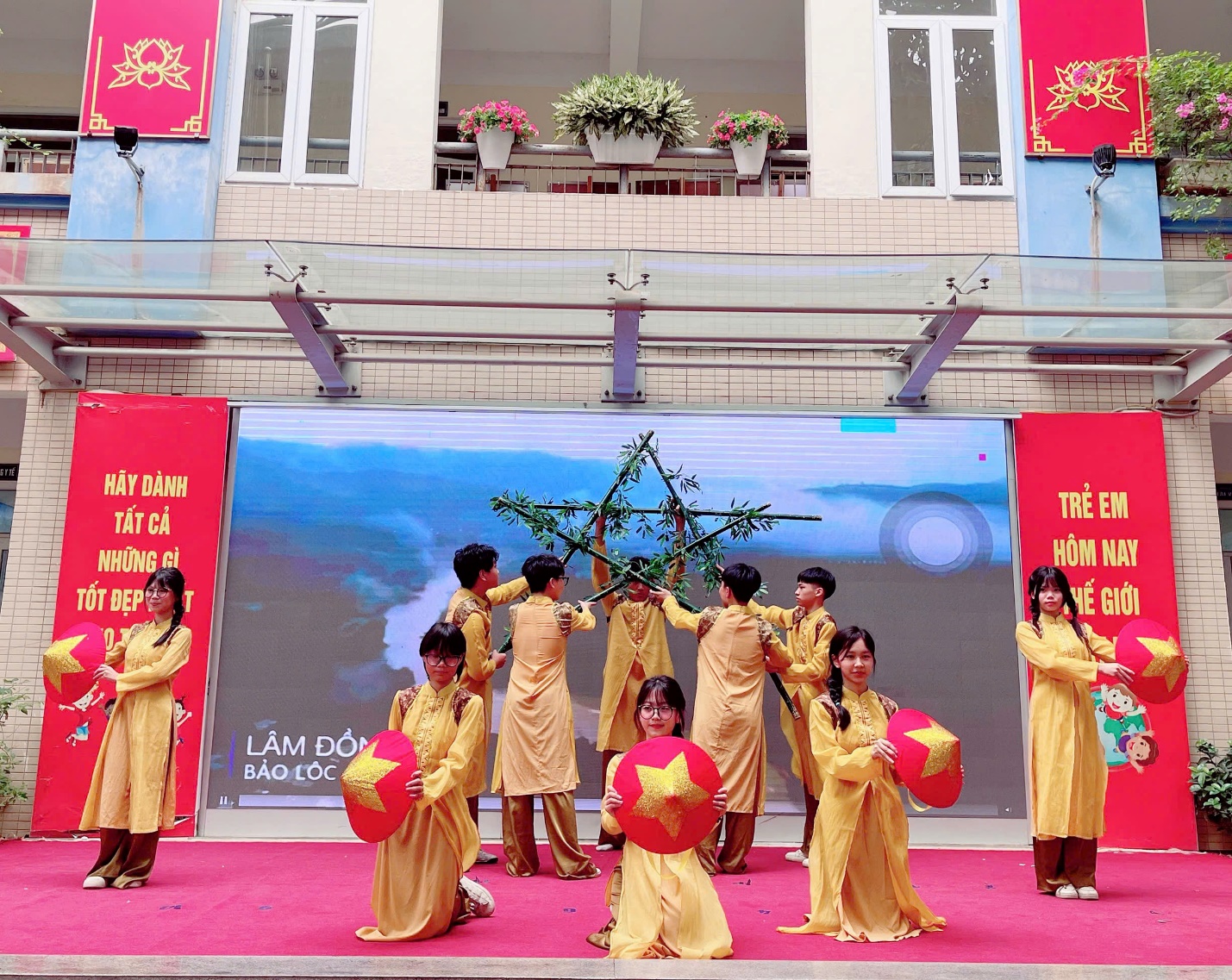 A group of people in yellow dresses holding red pillowsDescription automatically generated