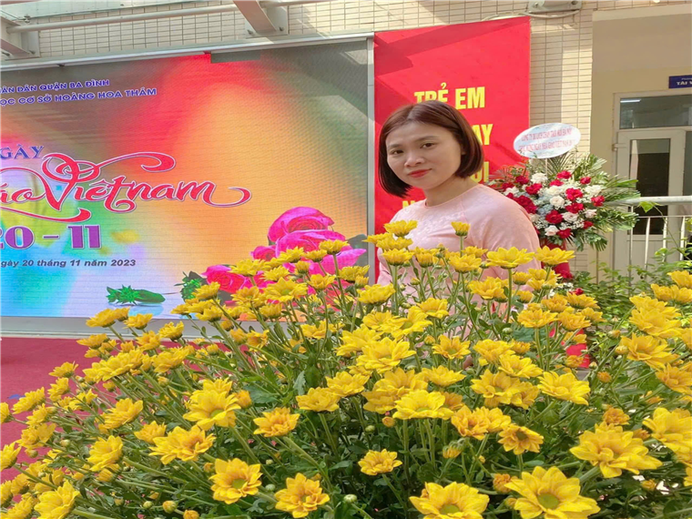 A person standing in front of a large yellow flowerDescription automatically generated