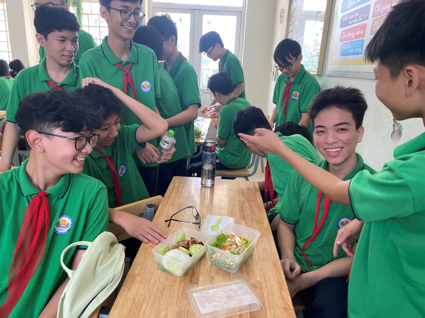 A group of boys in green shirts sitting at a table with food

Description automatically generated