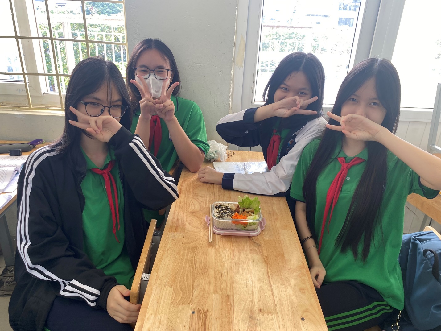 A group of girls sitting at a table with their hands up

Description automatically generated
