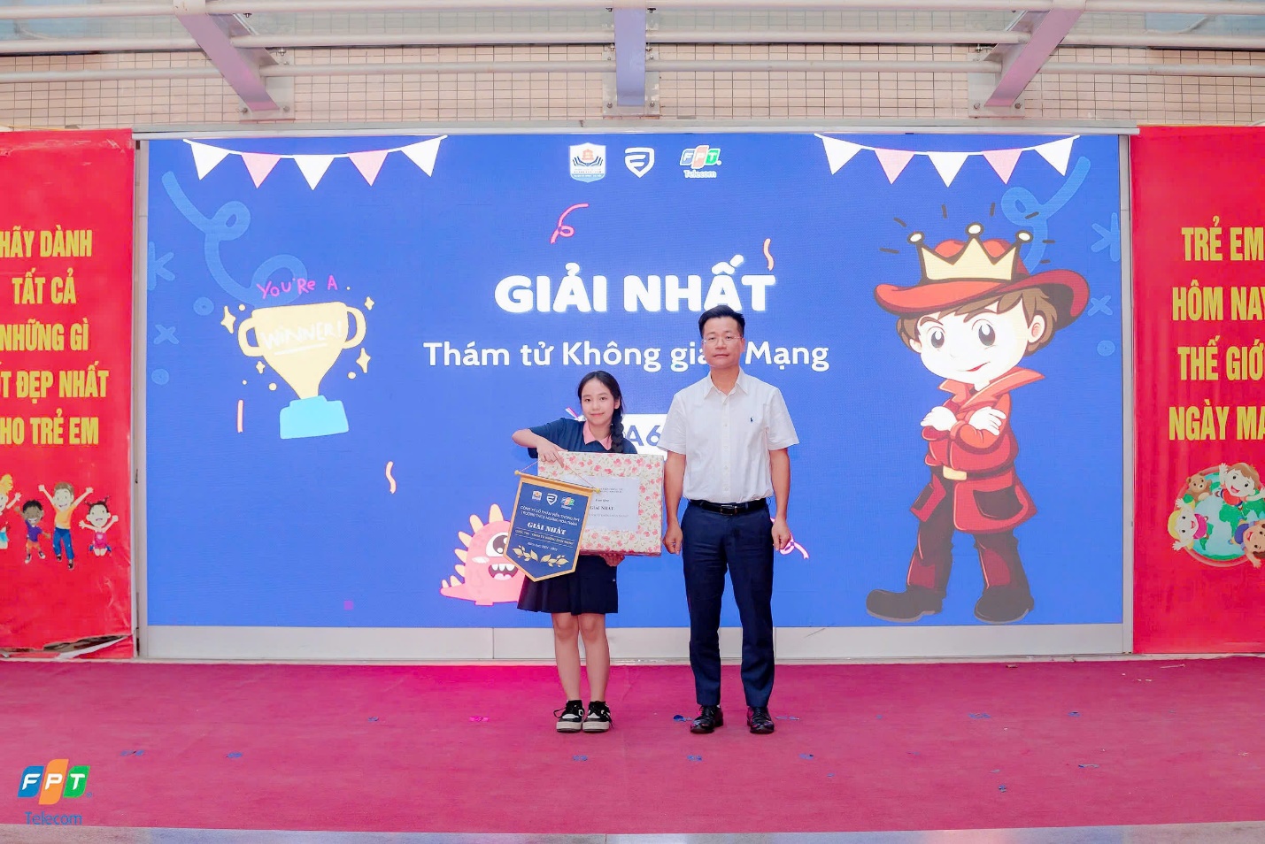 A person and person standing in front of a large blue bannerDescription automatically generated
