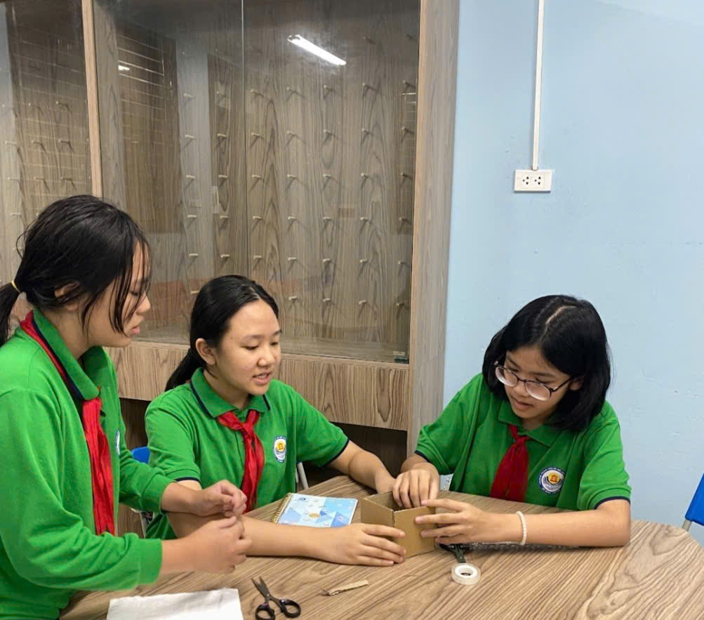 A group of girls in green shirts sitting at a tableDescription automatically generated