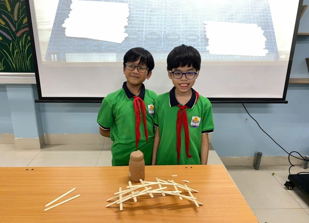 Two boys in uniform standing next to a tableDescription automatically generated