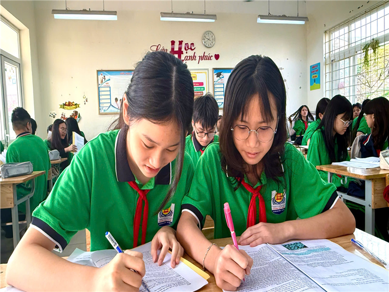 A group of girls in green uniforms writing on paper

Description automatically generated