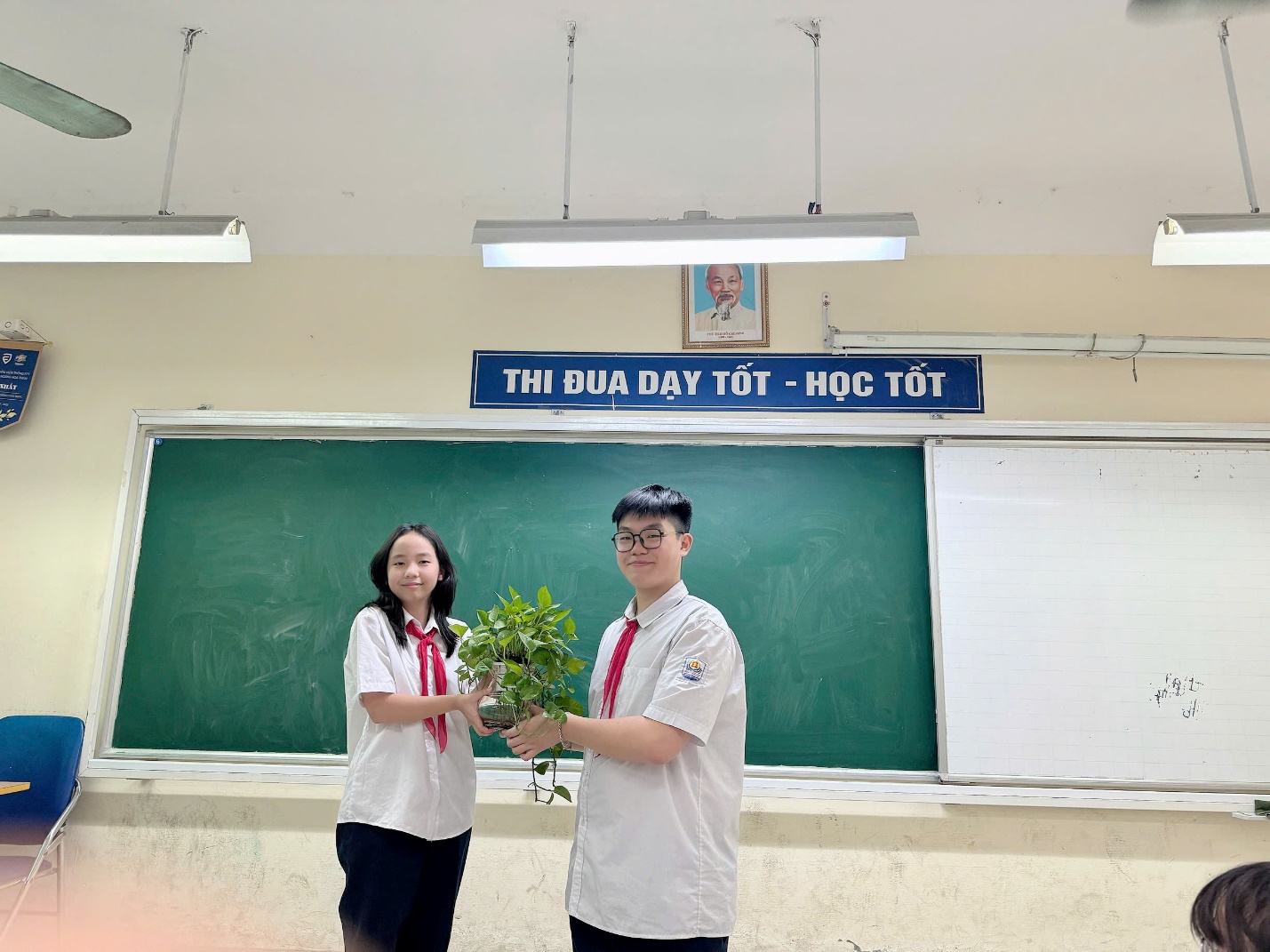 A person and person holding plants in front of a chalkboard

Description automatically generated