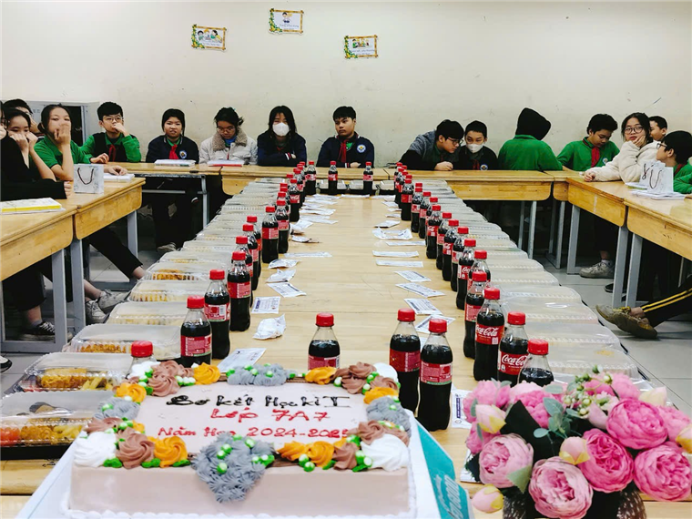 A group of people sitting at a table with drinks and cake

Description automatically generated