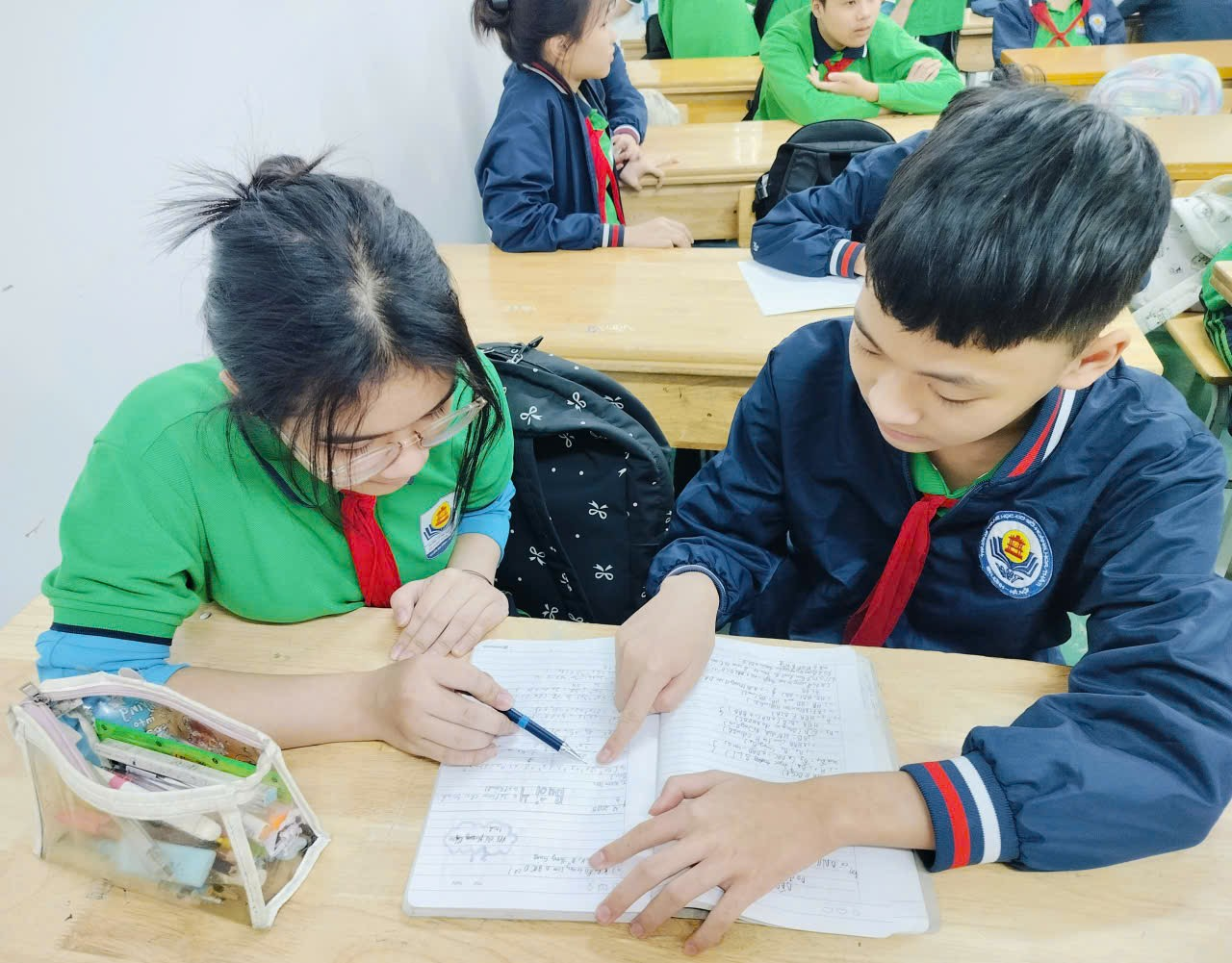A child and child sitting at a desk looking at a book

Description automatically generated