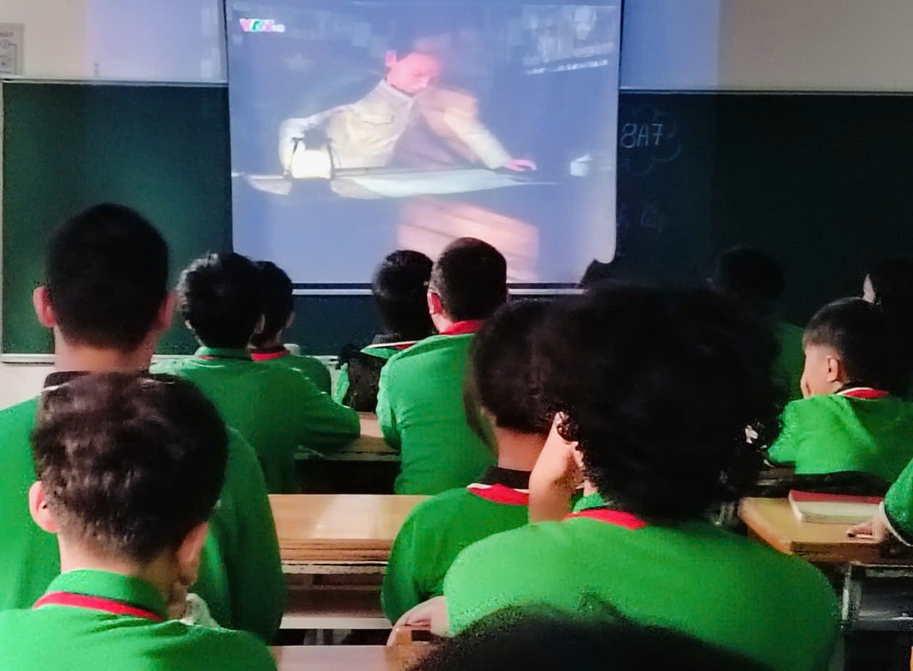 A group of people in a classroom watching a video

Description automatically generated