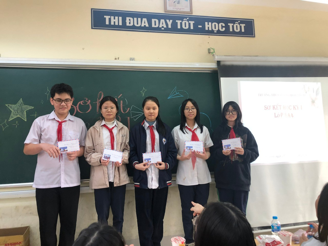 A group of people standing in front of a chalkboard

Description automatically generated