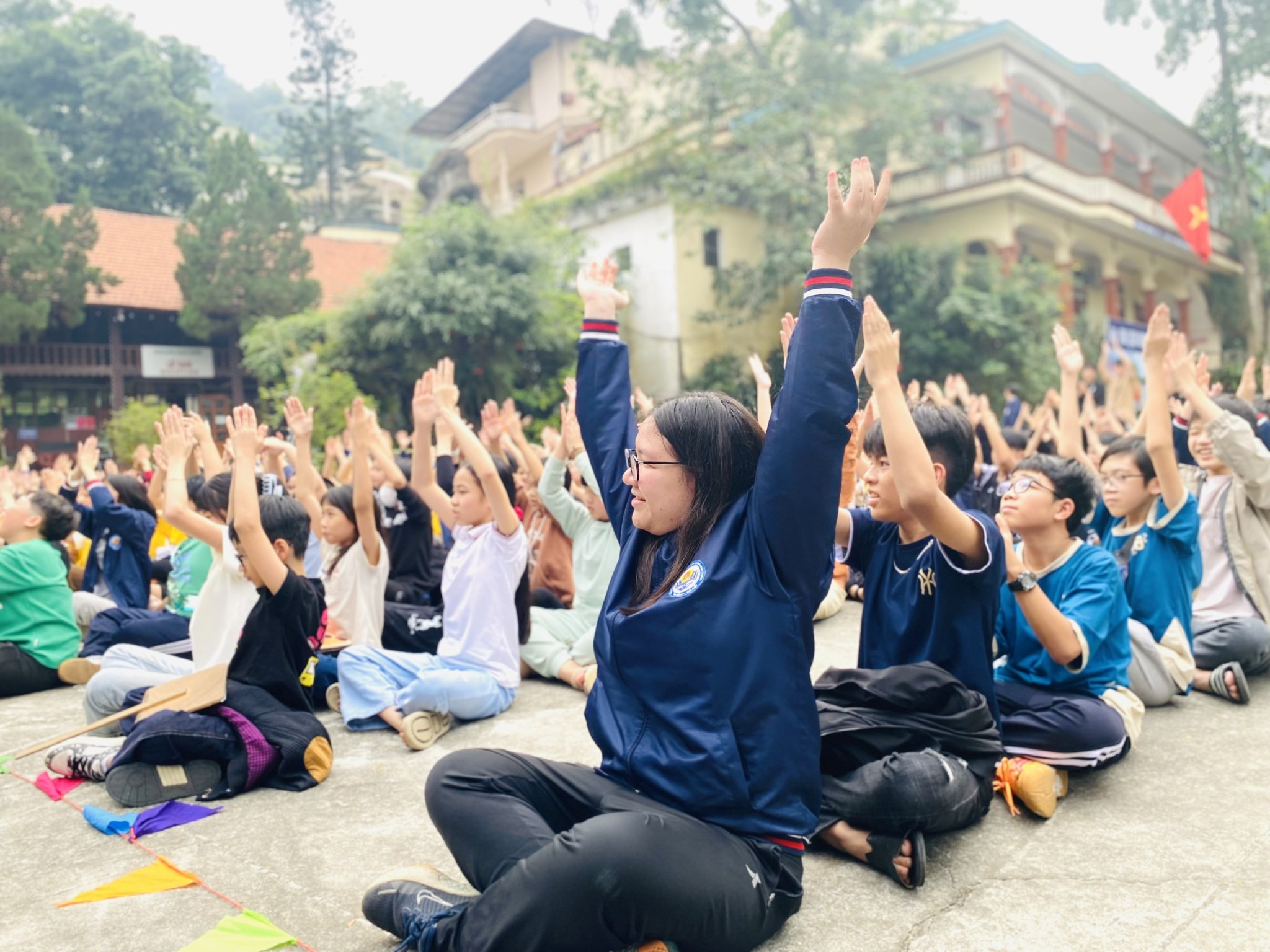 A group of people sitting on the ground with their hands up

AI-generated content may be incorrect.