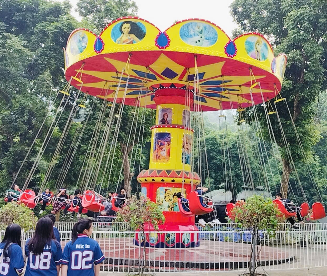 A group of people standing around a carousel
Description automatically generated