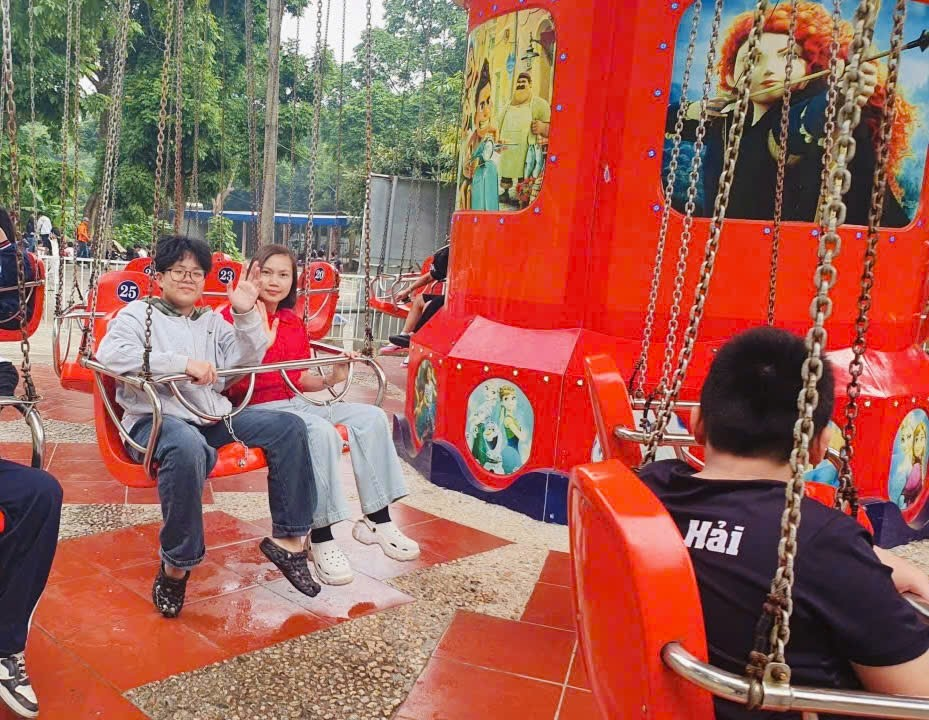 A group of people sitting on a swing
Description automatically generated