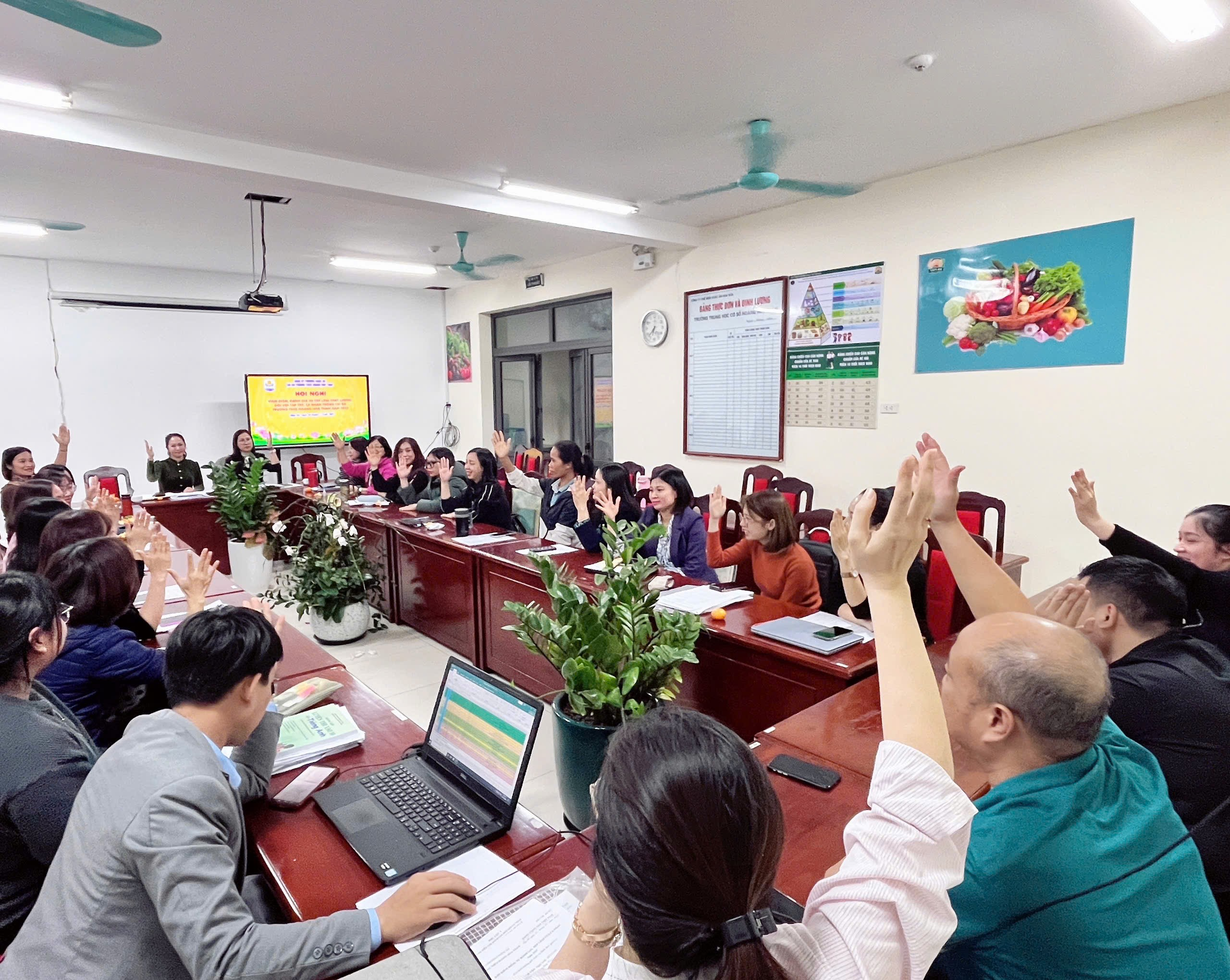 A group of people raising their hands in a meeting
Description automatically generated
