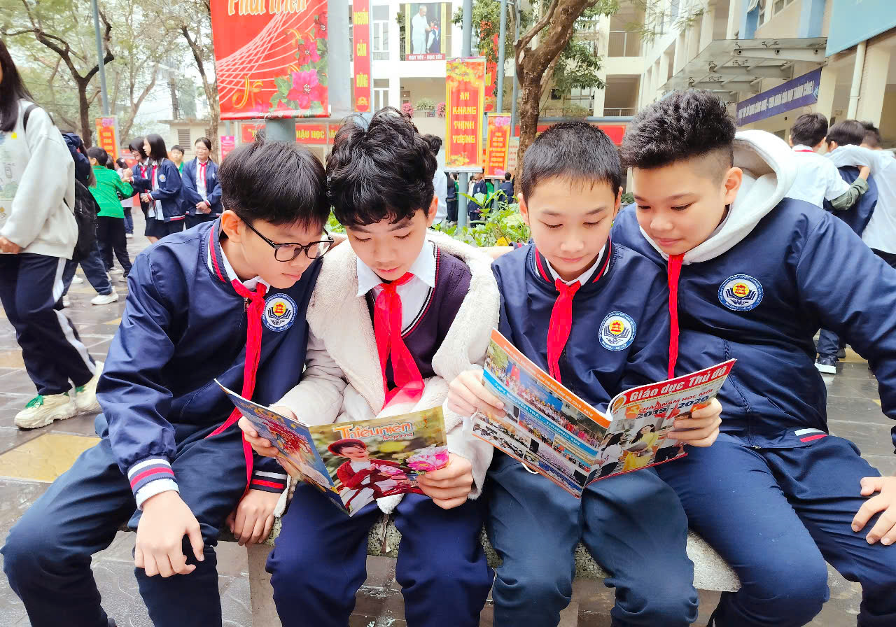 A group of boys sitting on a bench reading a book

Description automatically generated