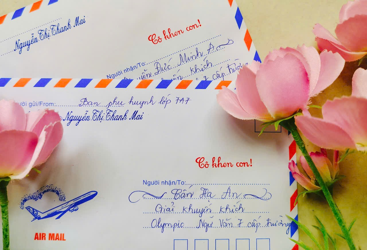 A pink flowers next to a envelope

Description automatically generated