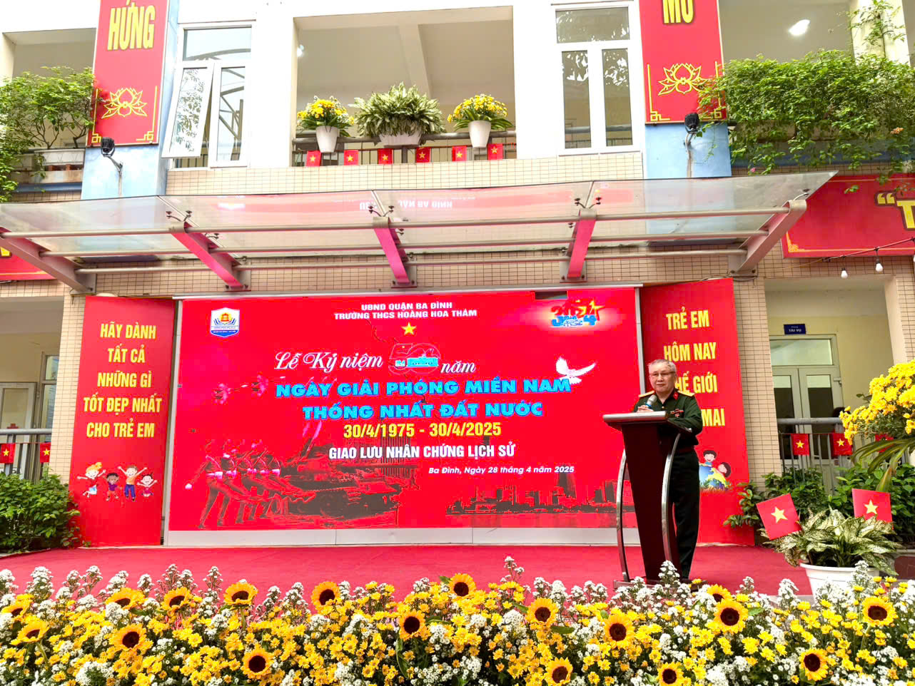 A person standing at a podium in front of a red banner

Description automatically generated