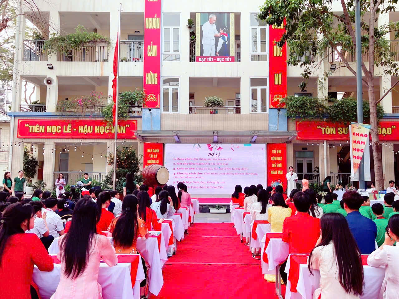 A group of people sitting on a red carpet outside a building

Description automatically generated