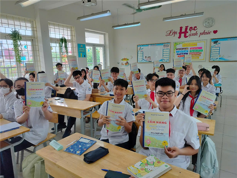 A group of people in a classroom holding up paper

Description automatically generated