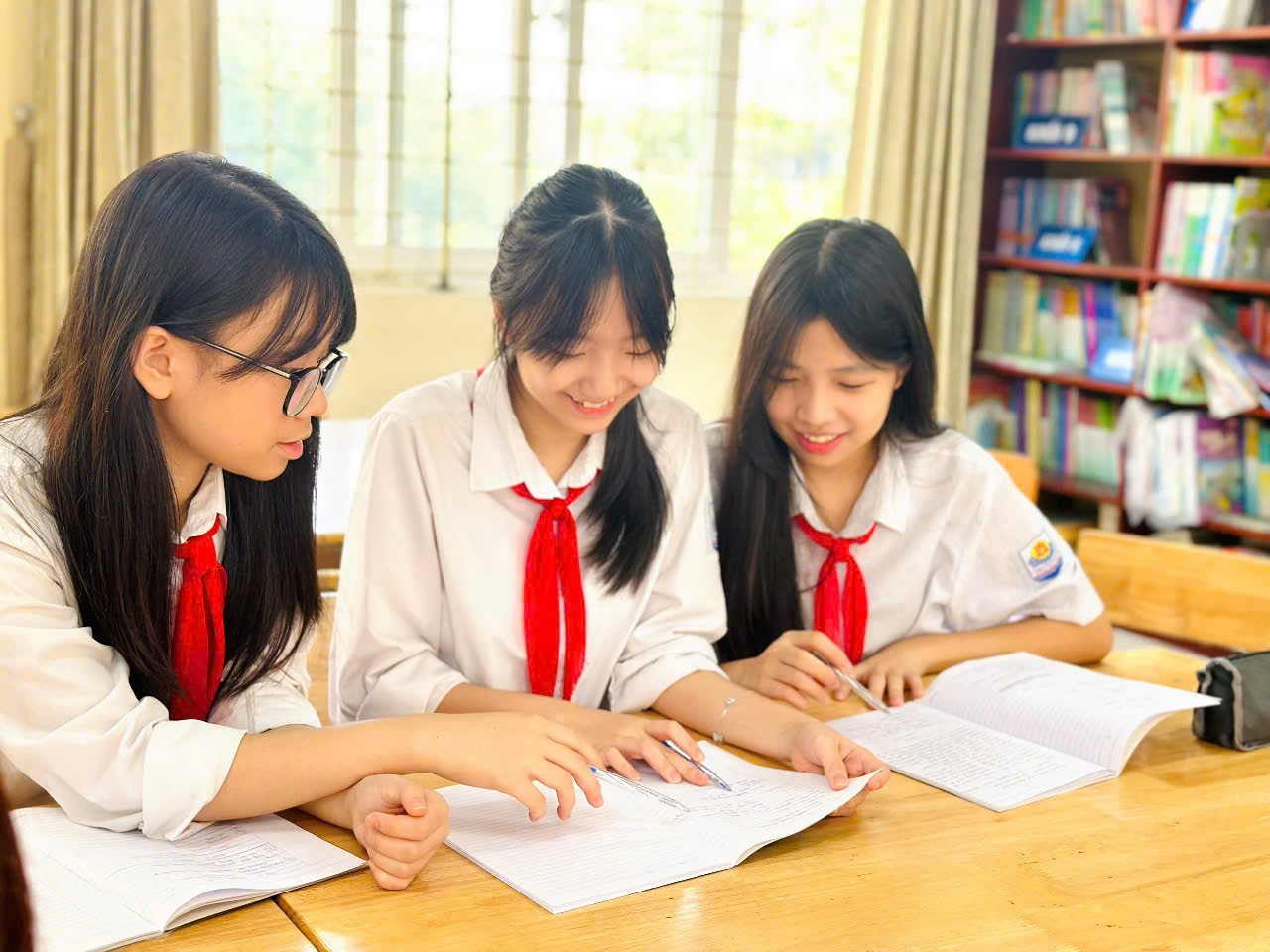 A group of girls in uniform looking at a book

Description automatically generated