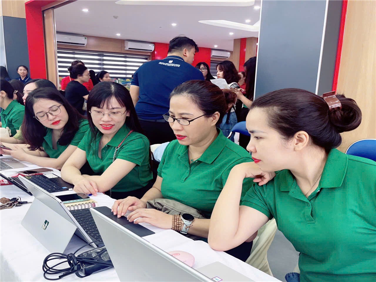 A group of women in green shirts sitting at a table with laptops

Description automatically generated