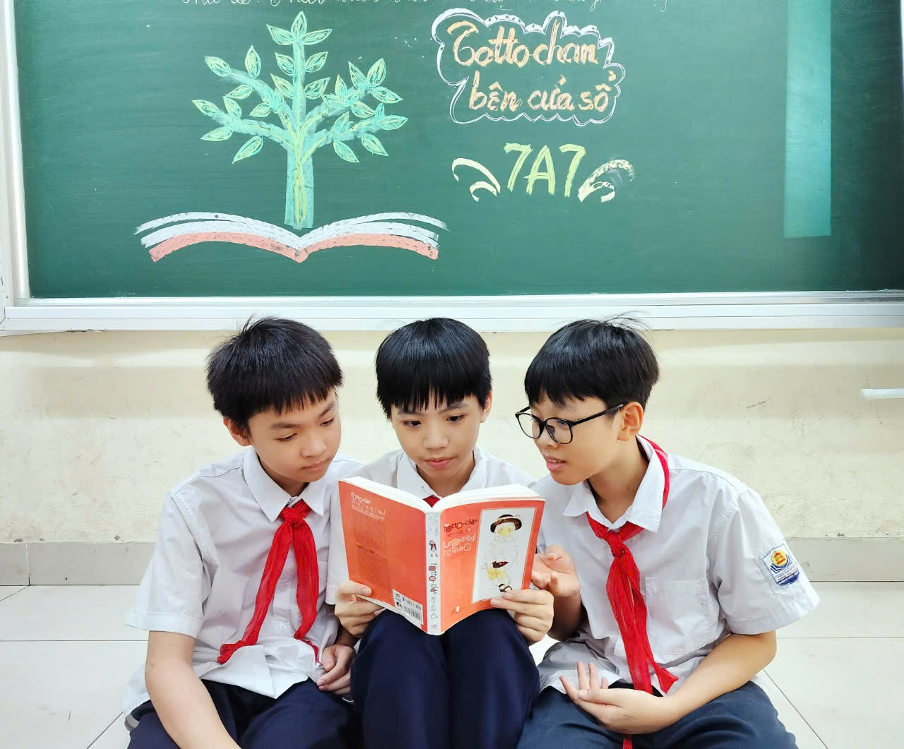 A group of boys sitting on the floor reading a bookDescription automatically generated