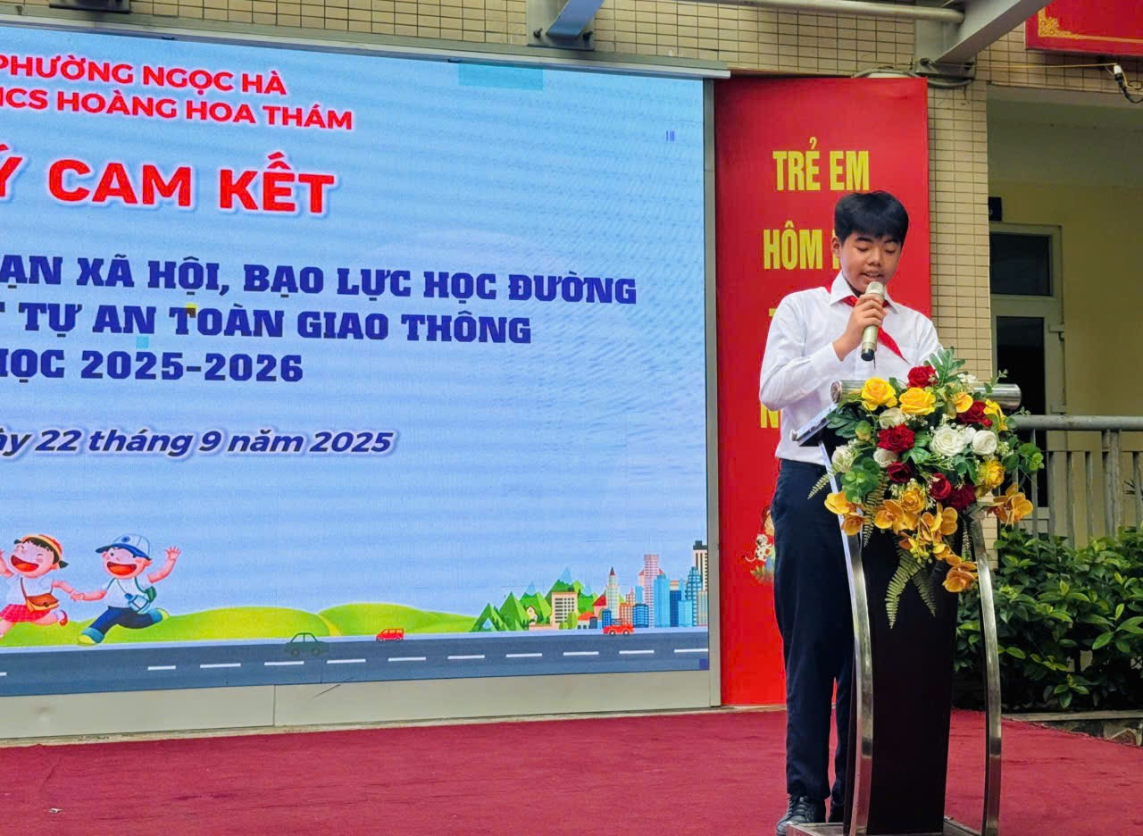 A person standing on a podium with a microphone and flowers
Description automatically generated
