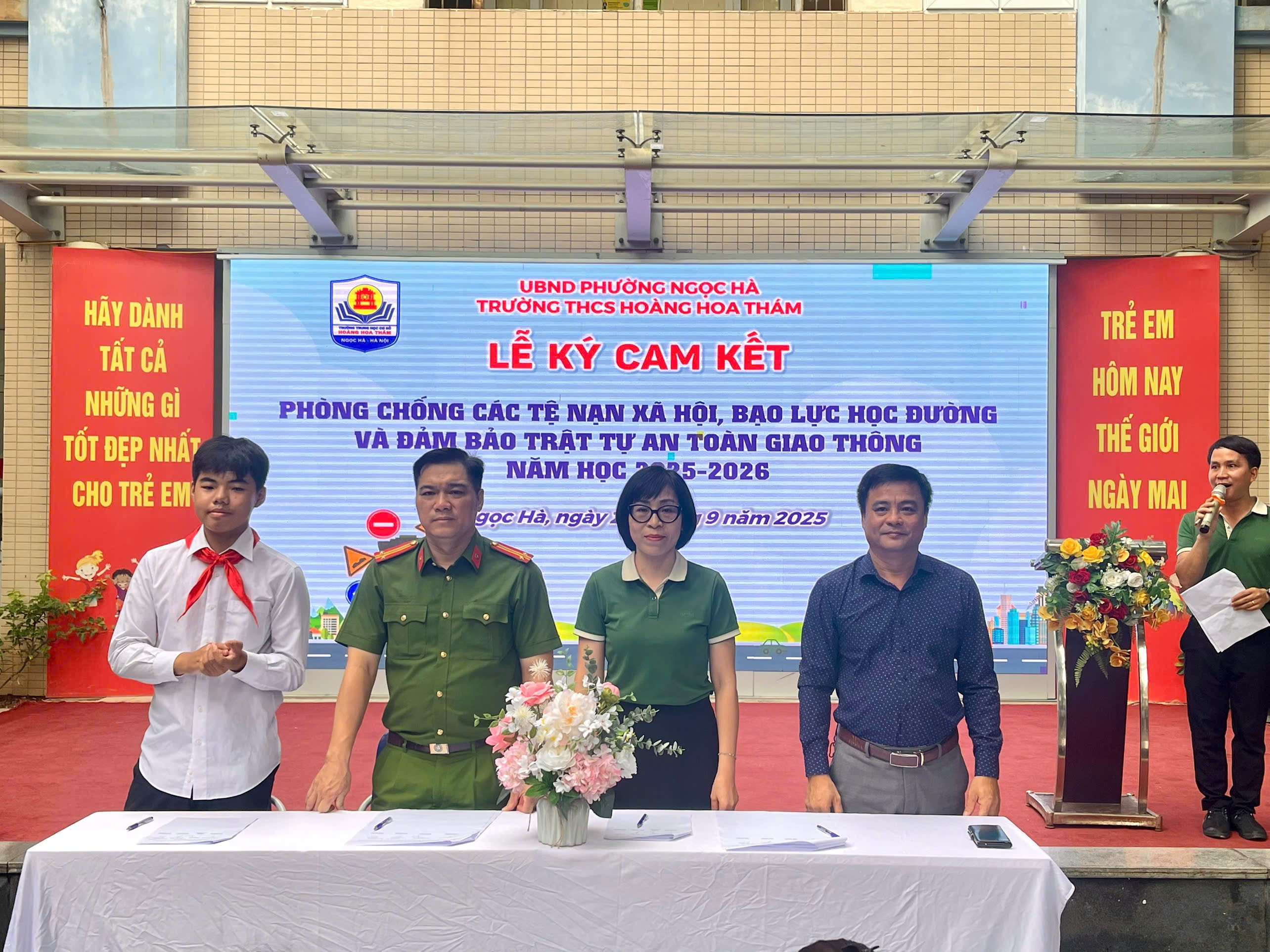 A group of people standing in front of a large screenDescription automatically generated