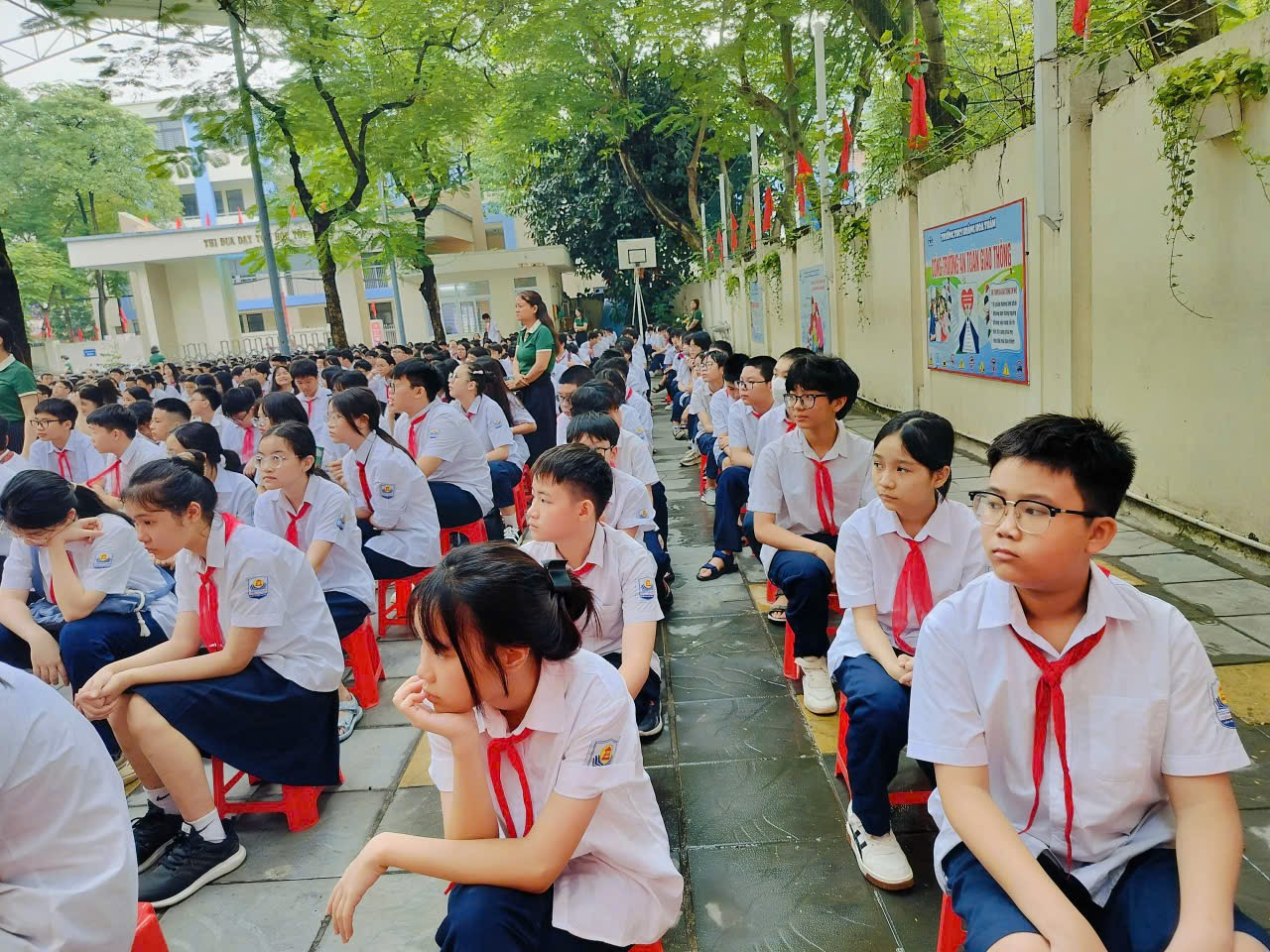 A group of students sitting on a sidewalk
Description automatically generated