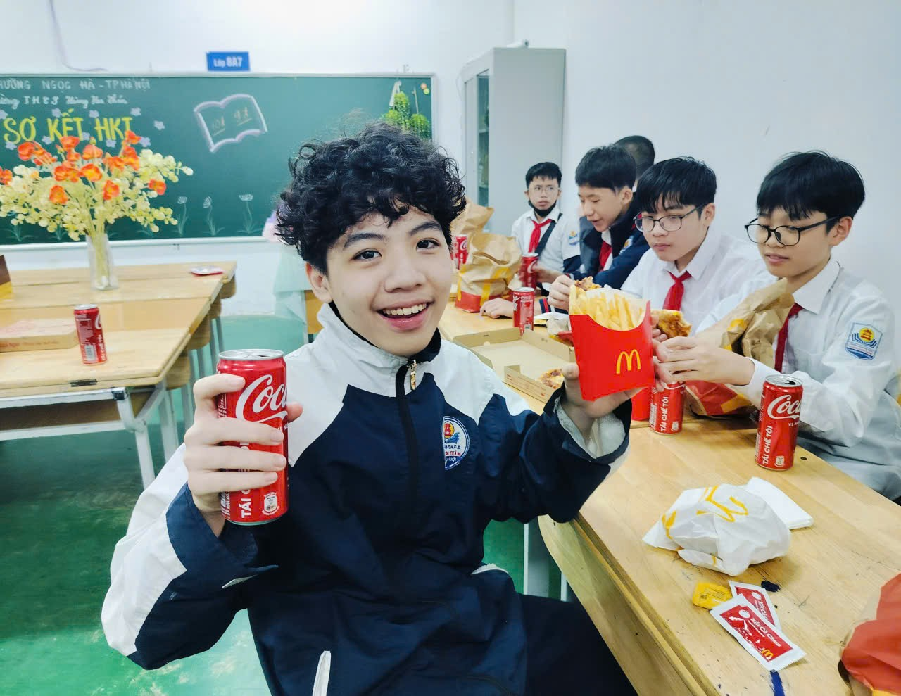 A group of people sitting at a table with food and soda

Description automatically generated