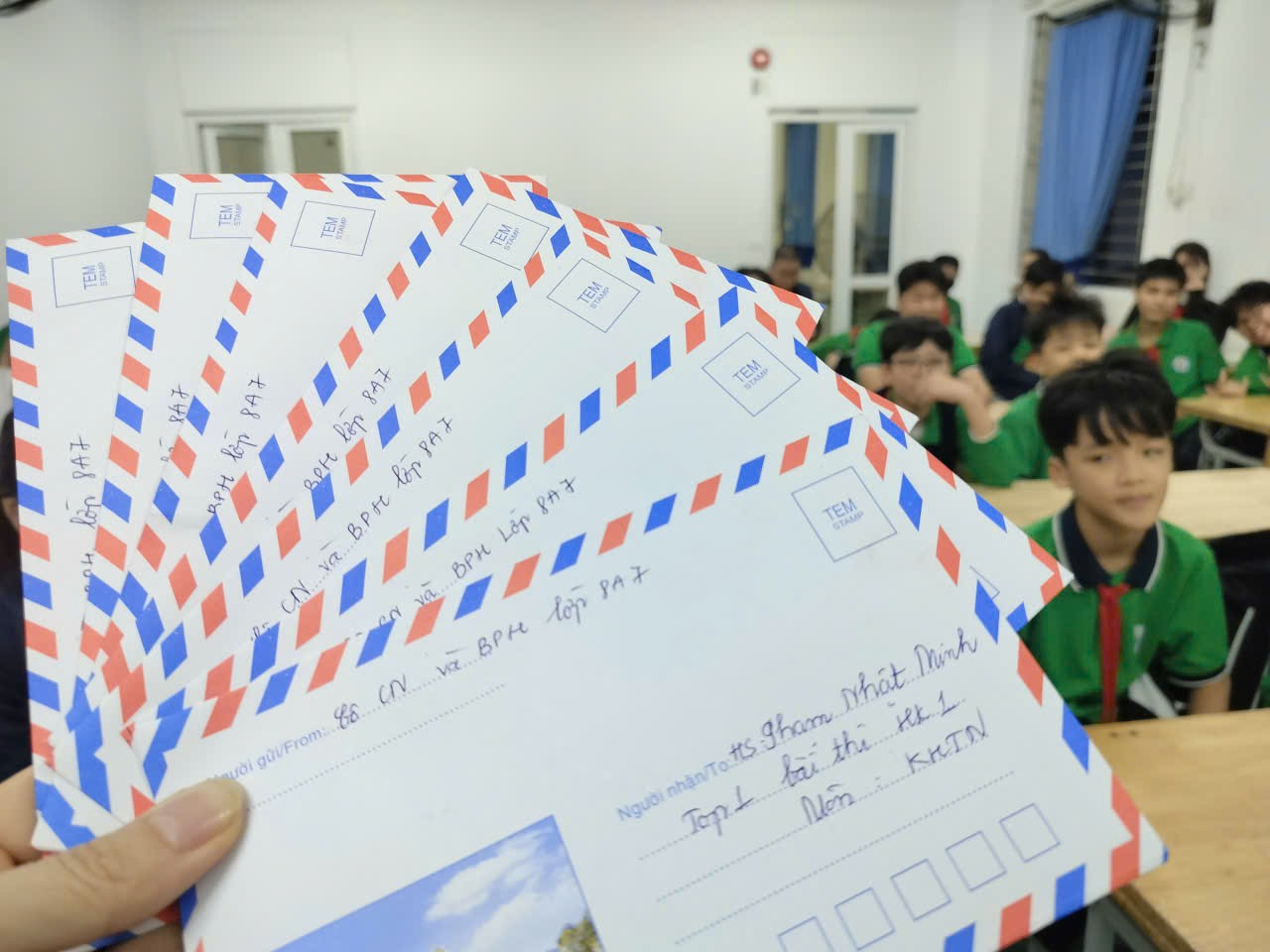 A hand holding a group of envelopes

Description automatically generated