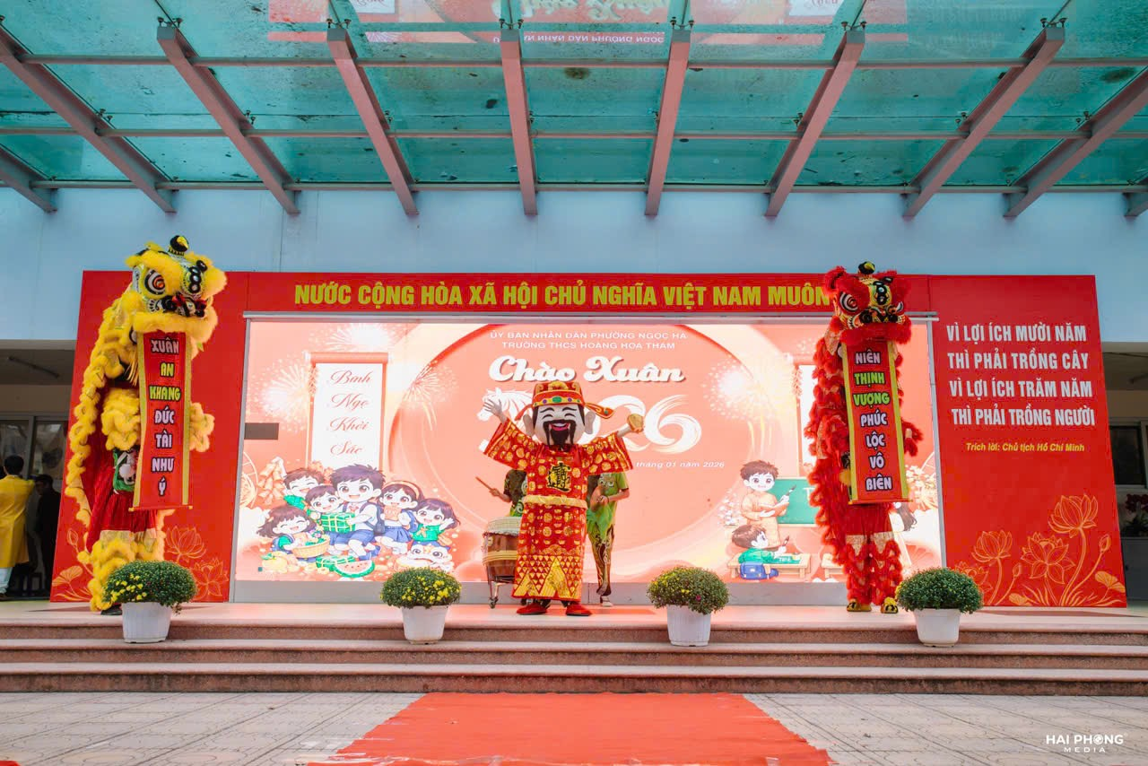A stage with a stage with a sign and a couple of people in clothing

Description automatically generated with medium confidence