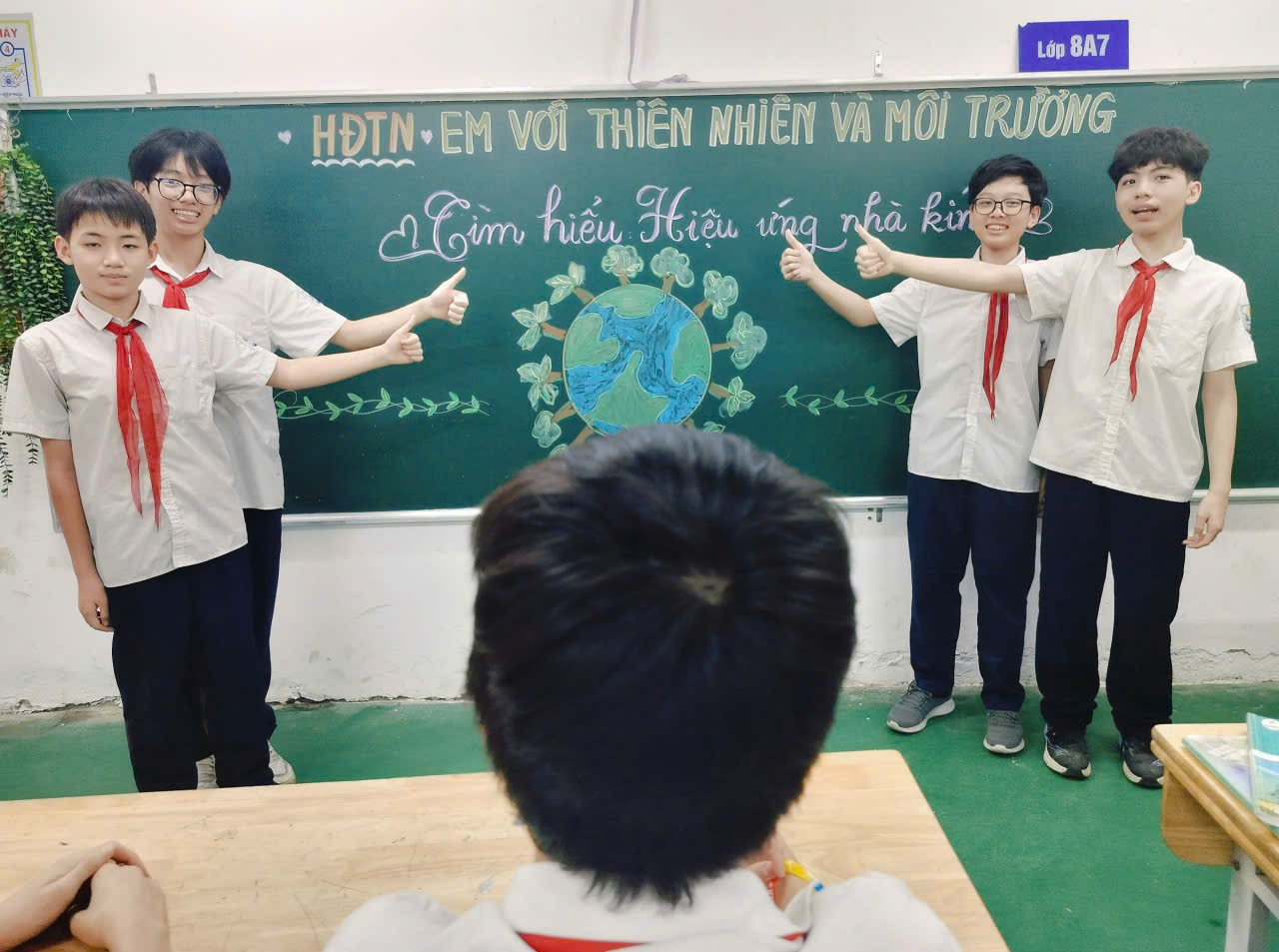 A group of people standing in front of a chalkboard

Description automatically generated