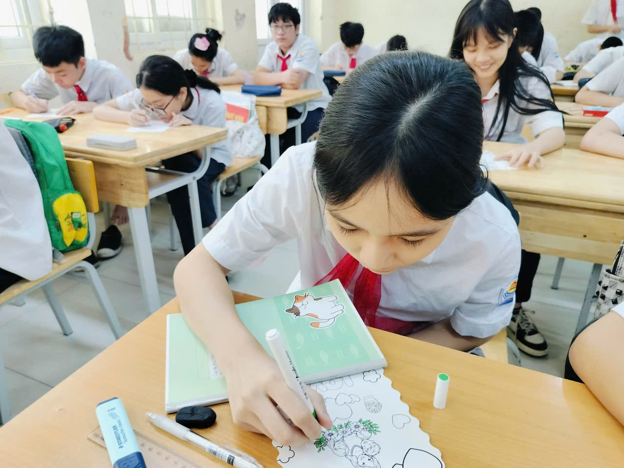 A child writing on a book in a classroom
Description automatically generated