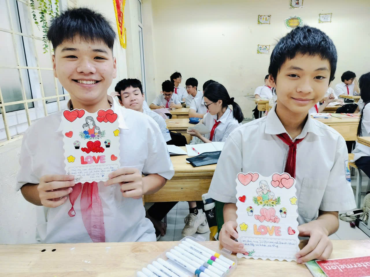 Two boys holding up a card
Description automatically generated