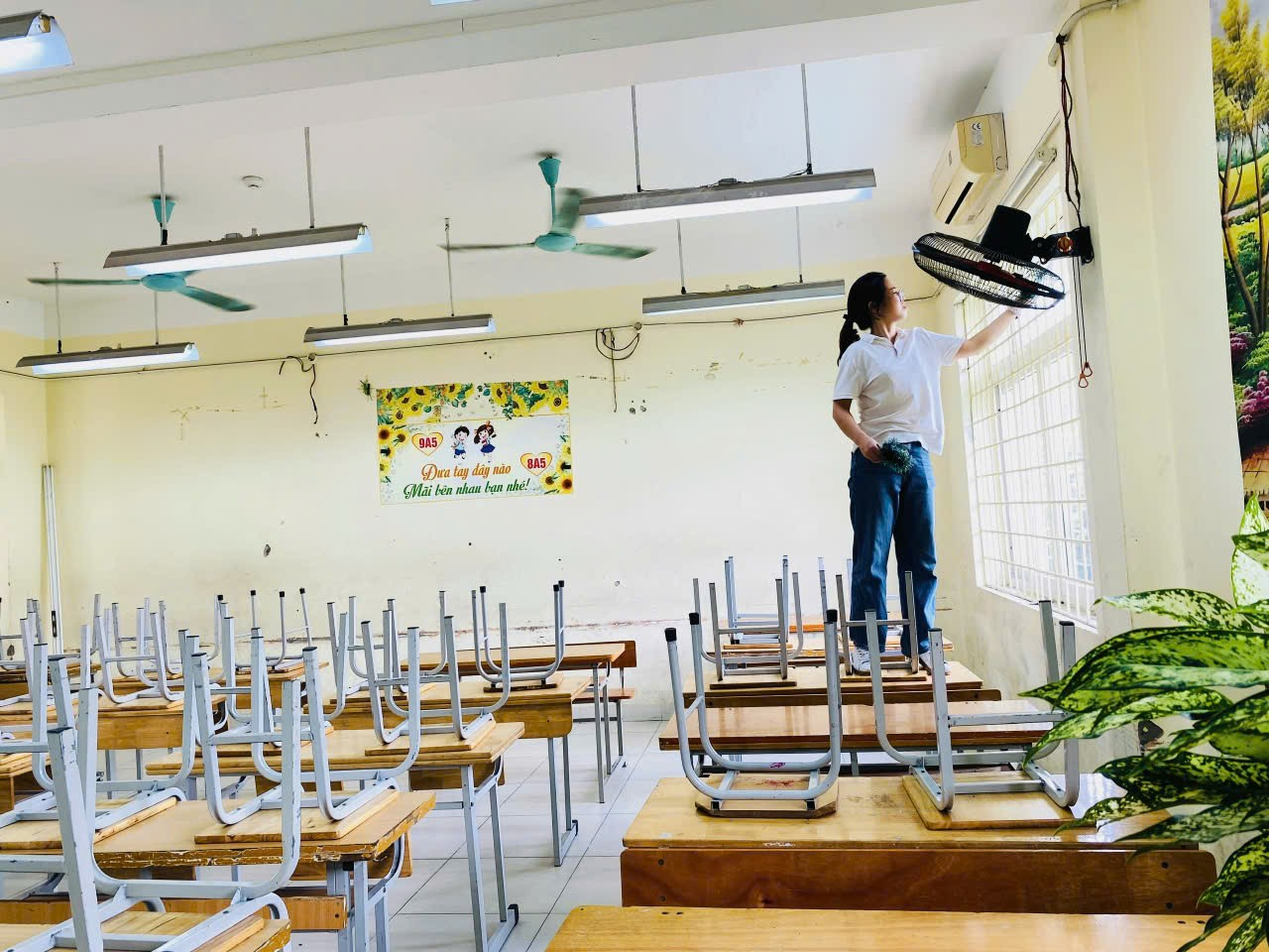 A person standing on desks in a classroom

Description automatically generated
