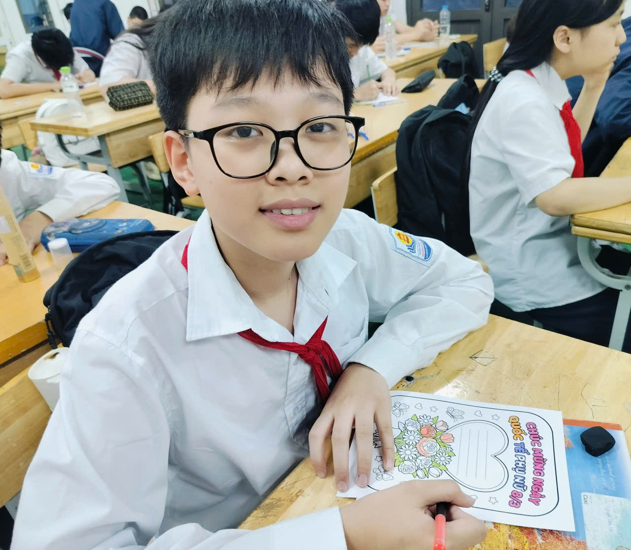 A child in a white shirt and glasses sitting at a desk
Description automatically generated