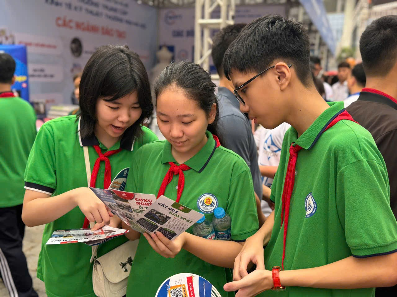 A group of people in green shirts looking at a piece of paper

Description automatically generated