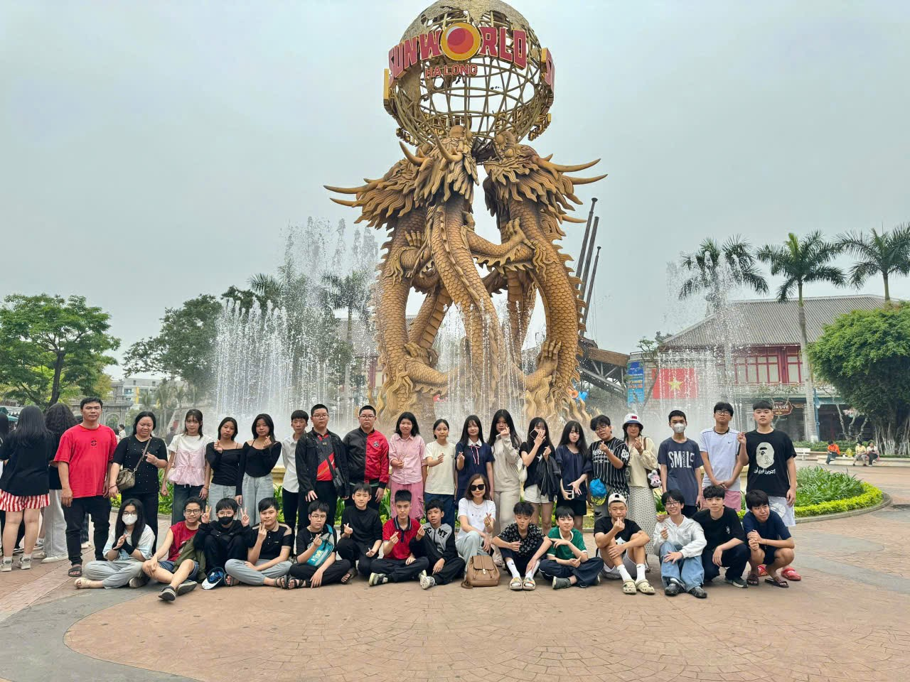 A group of people posing for a photo in front of a fountain
Description automatically generated