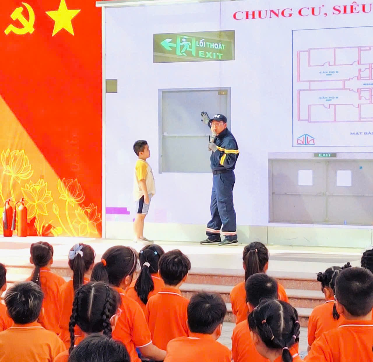 A person and child on stage with a large screenDescription automatically generated