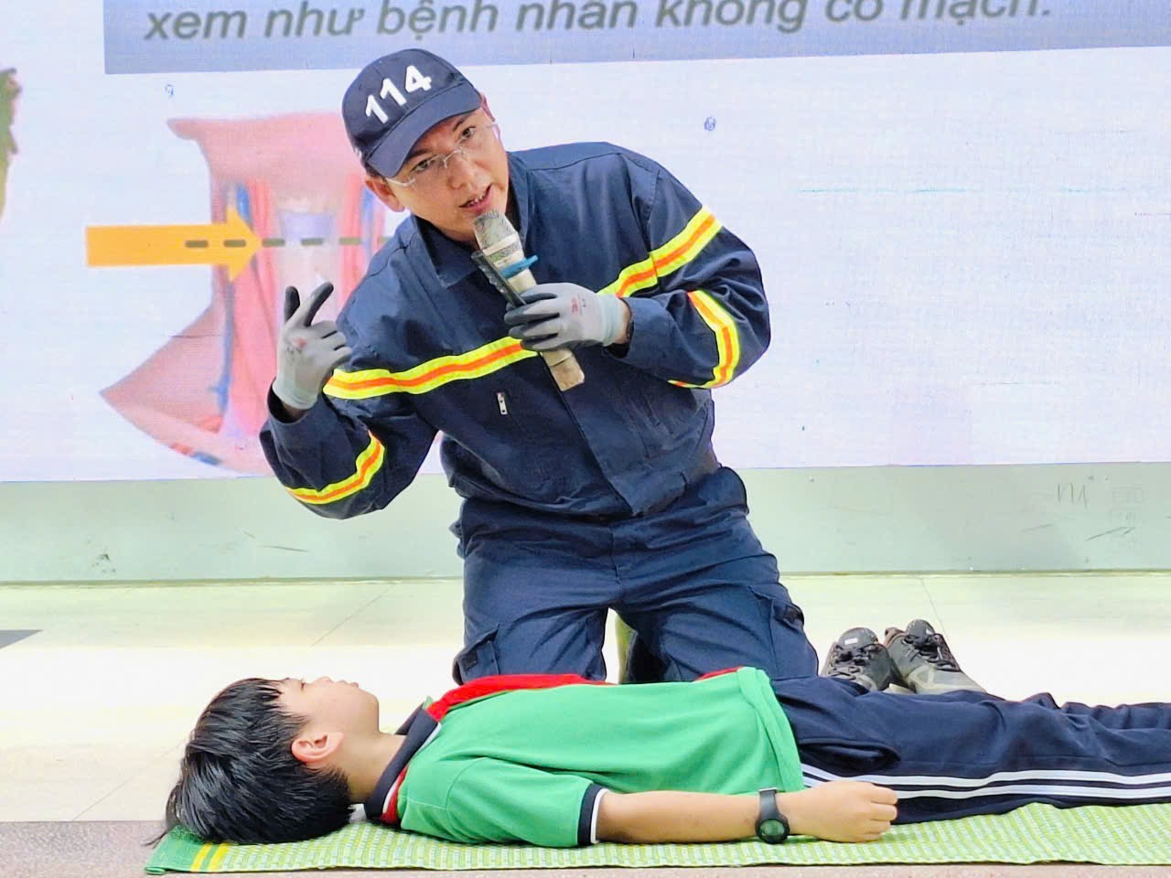 A person in uniform holding a microphone and lying on the groundDescription automatically generated