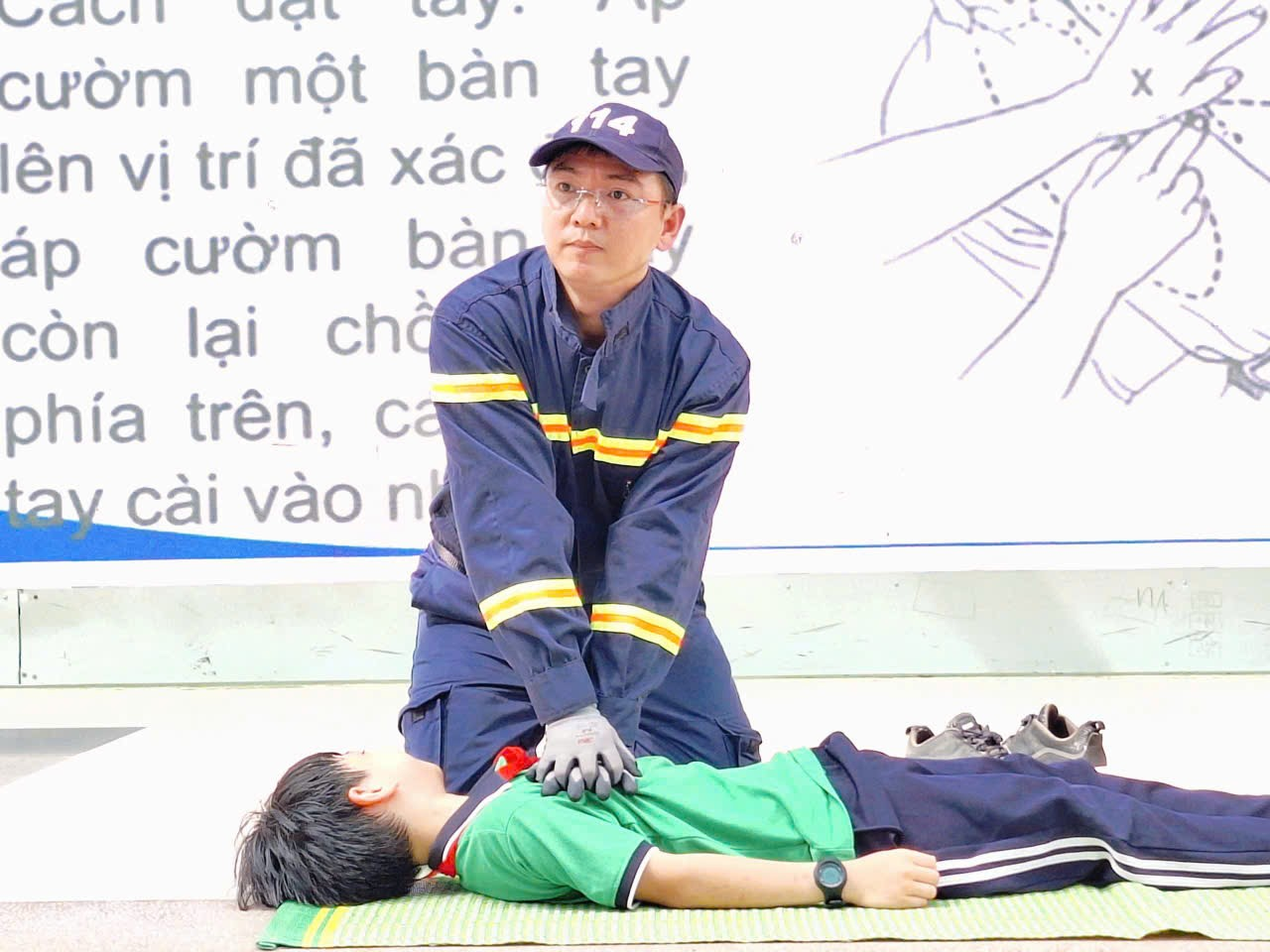 A person in uniform holding onto a child lying on the groundDescription automatically generated
