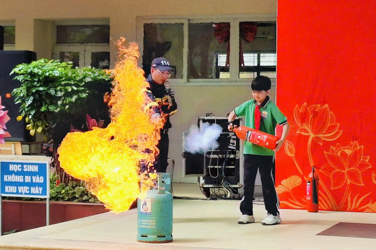 A person and child standing next to a fire extinguisherDescription automatically generated