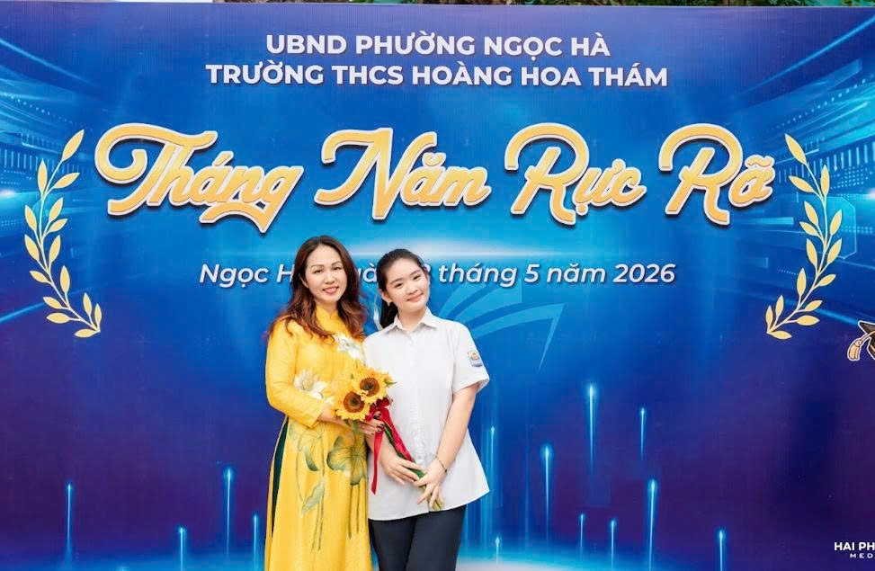 Two women standing in front of a signDescription automatically generated