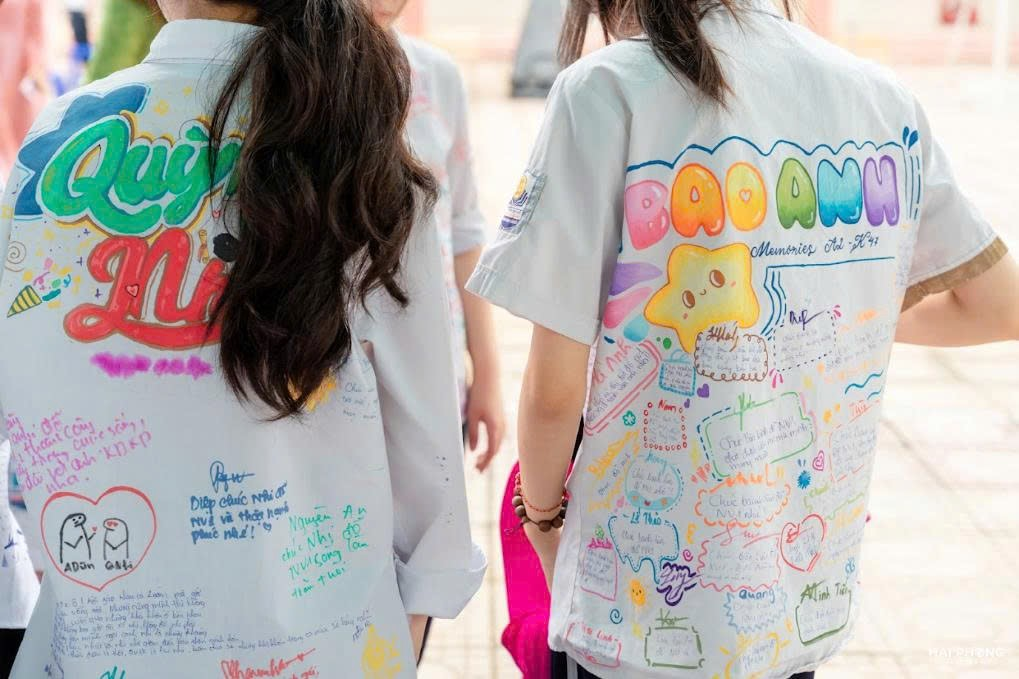 A couple of girls wearing white t-shirts with writing on themDescription automatically generated