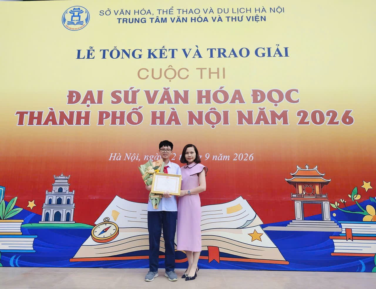 A person and person standing in front of a bannerDescription automatically generated